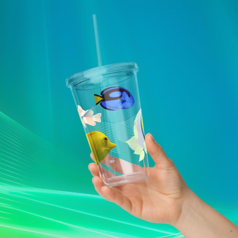 Hand holding a tropical fish insulated tumbler with straw on aqua background